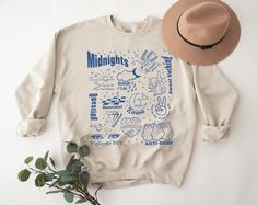 a white sweatshirt with blue writing on it and a brown hat sitting next to it