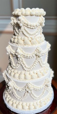 a white wedding cake with pearls on it's sides and an intricately decorated top