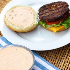 a hamburger on a plate next to a cup of coffee