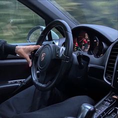 a man sitting in the driver's seat of a car with his hand on the steering wheel