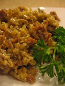 a white plate topped with pasta and meat next to parsley on top of it