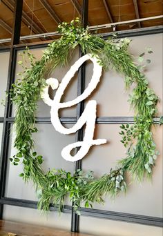 a sign with the word gly painted on it in front of a wall decorated with greenery