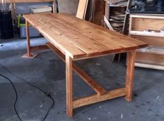 a wooden table sitting in a garage next to other woodworking tools and materials on the floor