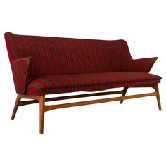 a red and black striped couch sitting on top of a wooden frame with two legs