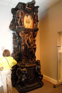 a woman standing next to a tall wooden clock