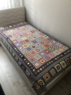 a crocheted bedspread on a bed in a room with white walls