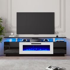 an entertainment center with a large television and blue flames on the side, in front of a white wall