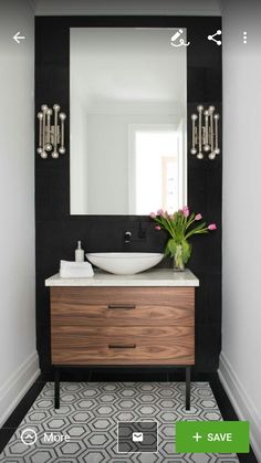 a black and white bathroom with a wooden vanity, large mirror and flowers on the counter