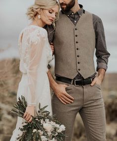 a man and woman standing next to each other in the desert with flowers on their bouquets