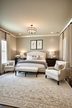 a large white bed sitting in a bedroom next to two chairs and a rug on top of a hard wood floor