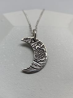 This unique silver moon necklace has been entirely handmade using .999 fine silver.  It has been cut from fine silver precious metal clay, textured, fired and oxidized. The pendant hangs from a sterling silver diamond cut cable chain. This fine silver pendant features an embossed floral leaf print pattern and hangs 7/8 inches from top of ring to bottom of the moon shape.   Pendant size: approximately 5/8 x 1/2 inches Chain length: adjustable at 16 and 18 inches                        can also be Silver Moon Necklace, Moon Necklace Silver, Leaf Print Pattern, Flower Moon, Precious Metal Clay, Moon Shape, Leaf Jewelry, Bohemian Necklace, Silver Moon