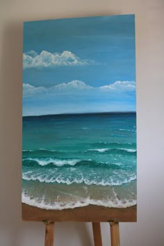 an easel is holding up a painting of the ocean