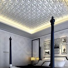 a large bed sitting under a ceiling in a bedroom next to two lamps and pictures on the wall