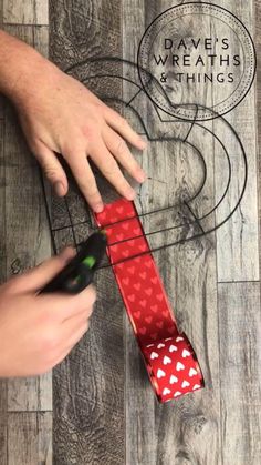 a person cutting up a red tie on top of a wooden floor next to a marker