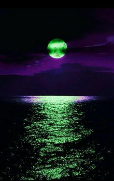 the moon is shining brightly over the ocean water at night with purple and green hues