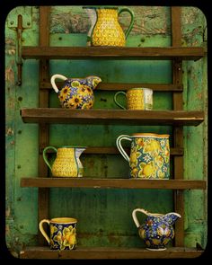 a wooden shelf filled with lots of different types of cups and saucers on top of it