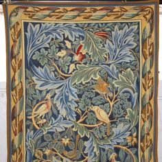 an intricately designed tapestry hanging on a wall with birds and leaves in the center