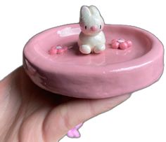 a hand holding a small pink object with a bunny in it