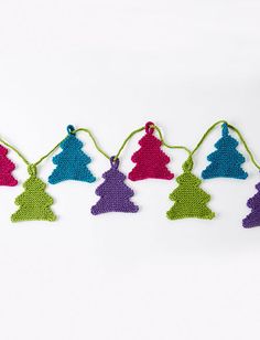 crocheted christmas tree ornaments hanging from string on white background with green and purple trim