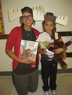 two girls holding stuffed animals and books in front of a wall with moose decorations on it