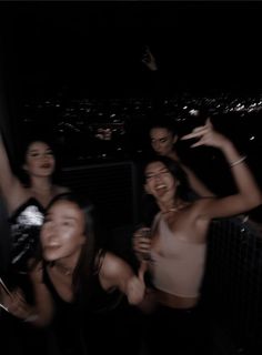 four girls are posing for the camera in front of a cityscape at night