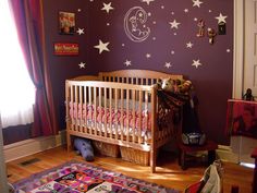 a baby's room with purple walls and white stars on the wall