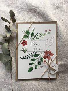 a card with some flowers on it next to a leafy branch and a tag