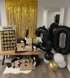 the table is set up with black and white balloons, gold foil streamers, and an 80 sign