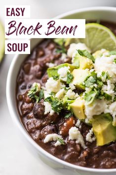 a white bowl filled with black bean soup and topped with avocado