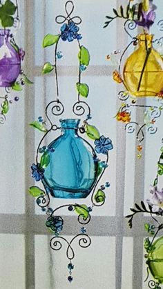 several colorful glass vases hanging from the side of a window with vines and flowers on them