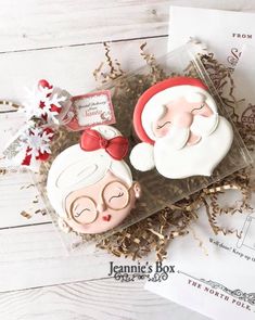 two cookies in the shape of santa and mrs claus sitting on top of a table