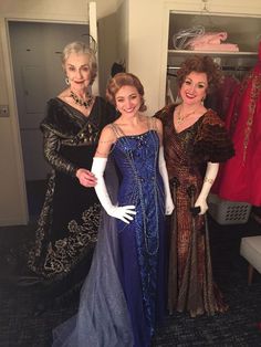 three women in evening gowns posing for a photo with one woman wearing gloves and the other holding her hand on her hip