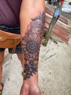 a person with a sunflower tattoo on their left arm and the other hand is holding something