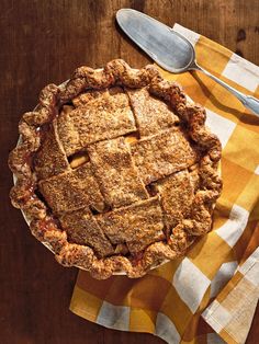 a pie sitting on top of a yellow and white checkered table cloth next to a fork