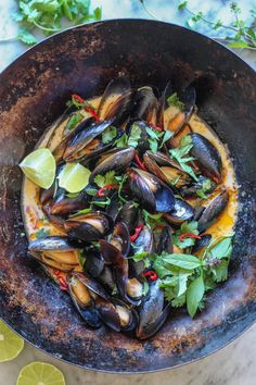 a pan filled with mussels and garnishes on top of a table