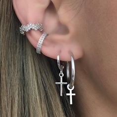 a woman's ear with two silver hoops and an anchor charm on it