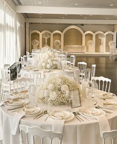 a banquet room set up with white tables and chairs