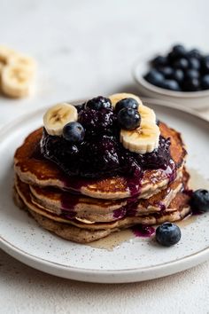 a stack of pancakes topped with blueberries and bananas