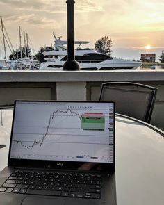 an open laptop computer sitting on top of a table next to a boat in the water