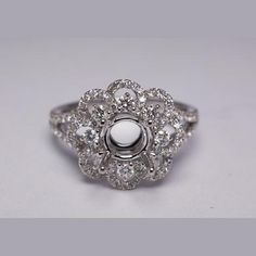 a white gold and diamond ring with an oval center surrounded by smaller round brilliant cut diamonds