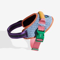 a small blue and pink dog harness with two colorful clips on it's side