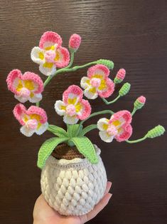 a crocheted vase with pink and white flowers in it