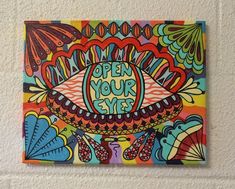 a colorful painting on the wall that says open your eyes with an eyeball in the center