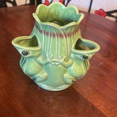 a green vase sitting on top of a wooden table