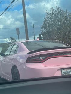 a pink car is parked on the side of the road in front of some bushes