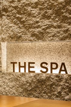 the spa sign is lit up in front of a stone wall with brown and white speckles