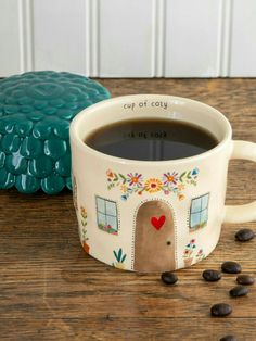 a cup of coffee sitting on top of a wooden table next to a blue cookie