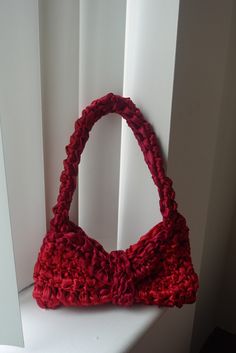 a red purse sitting on top of a window sill next to a white wall