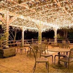 an outdoor dining area with tables and chairs covered in lights