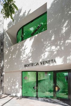 the entrance to bottega veneta is painted bright green and has glass doors